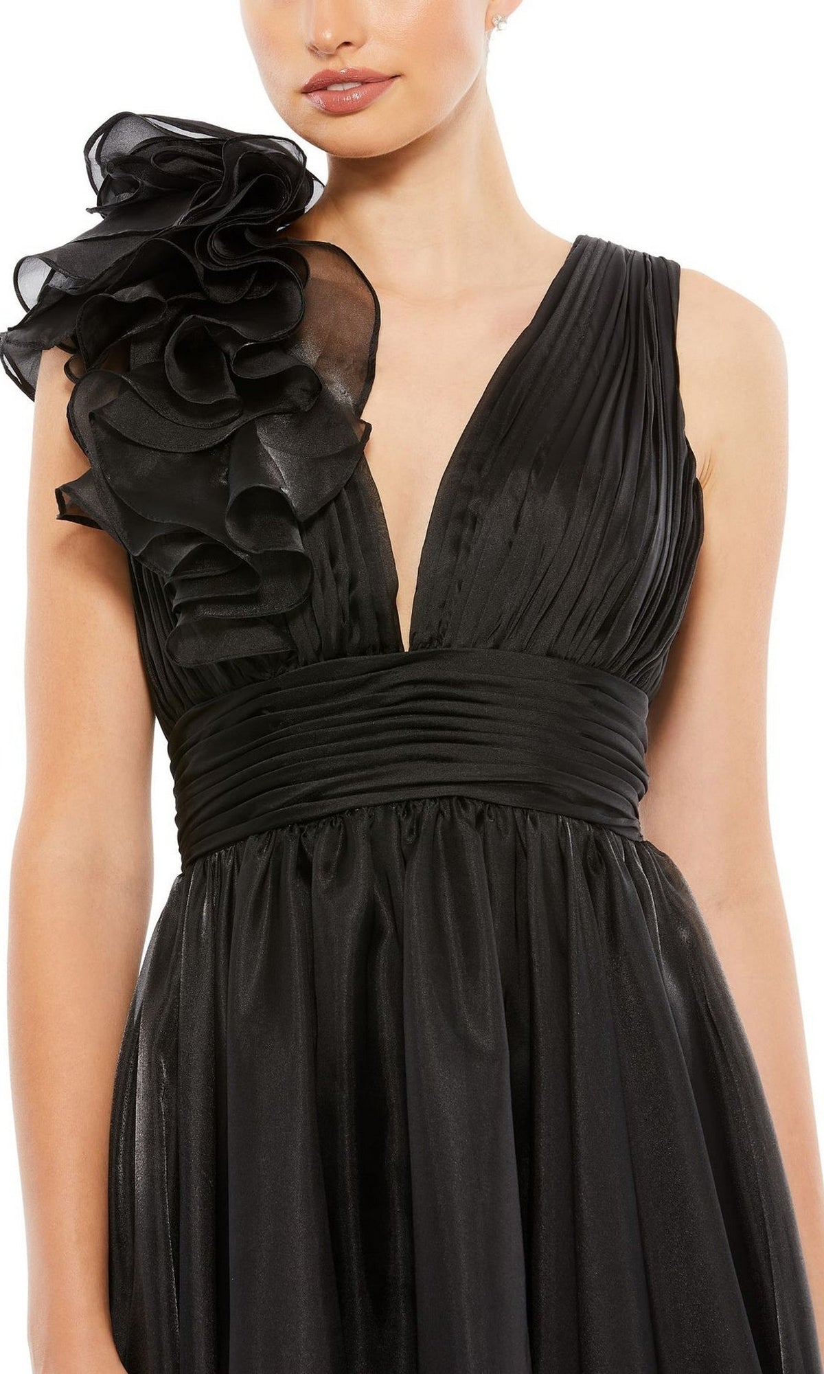 A woman wears the Mac Duggal Short Wedding Guest Dress 70165, a sleeveless black knee-length A-line dress with a deep V-neckline, pleated bodice, wide ruched waistband, and dramatic ruffled shoulder—ideal for special occasions.